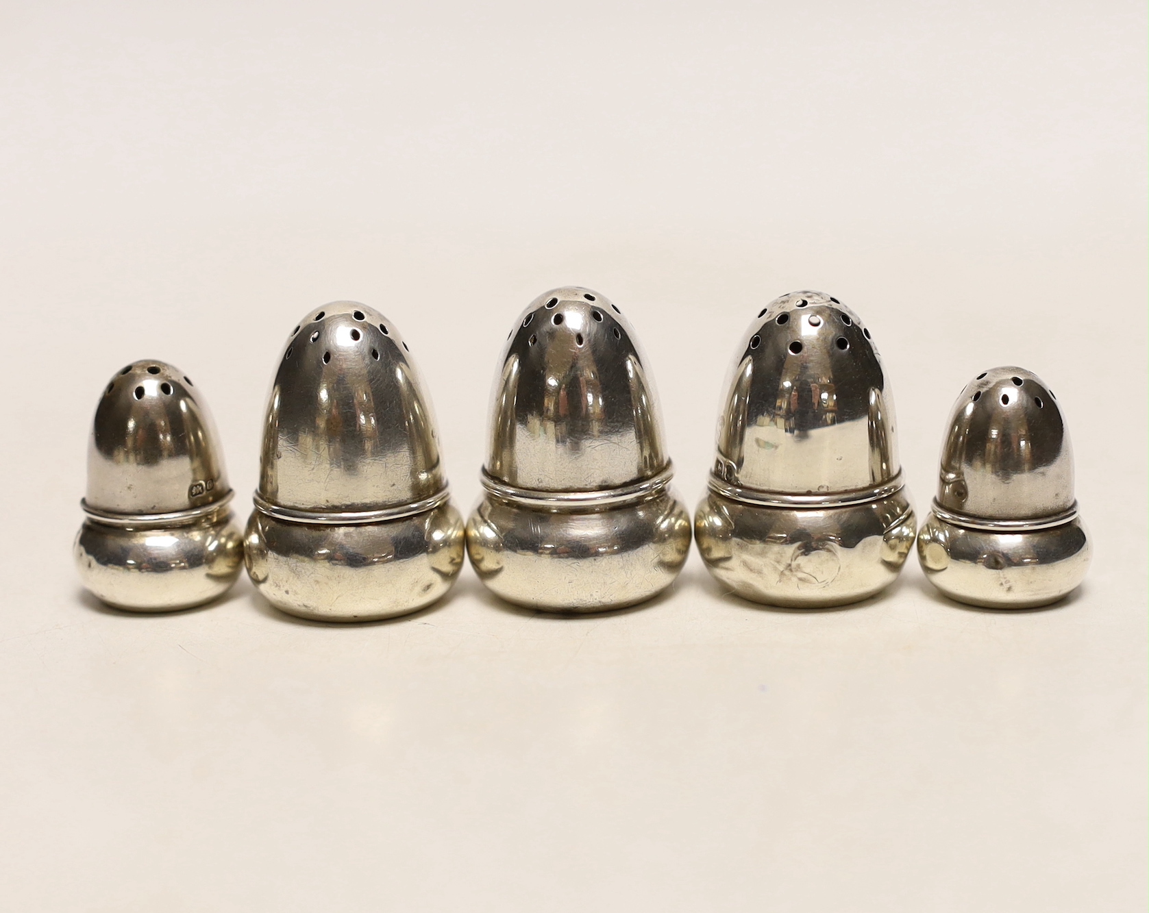 Two pairs of small Edwardian silver acorn pepperettes, the largest, Birmingham, 1903, 36mm and one other silver acorn pepperette.